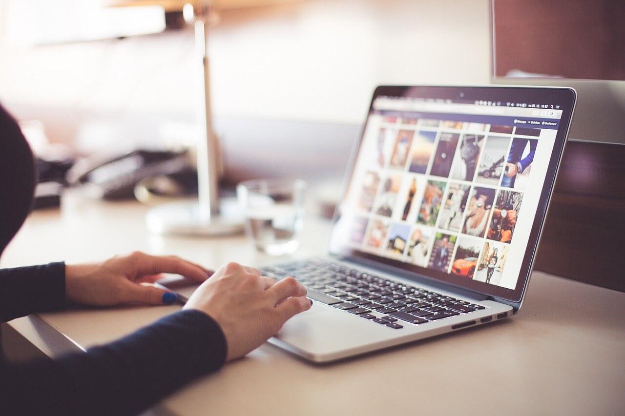 Person using their laptop to scroll through images, performing a social media investigation.